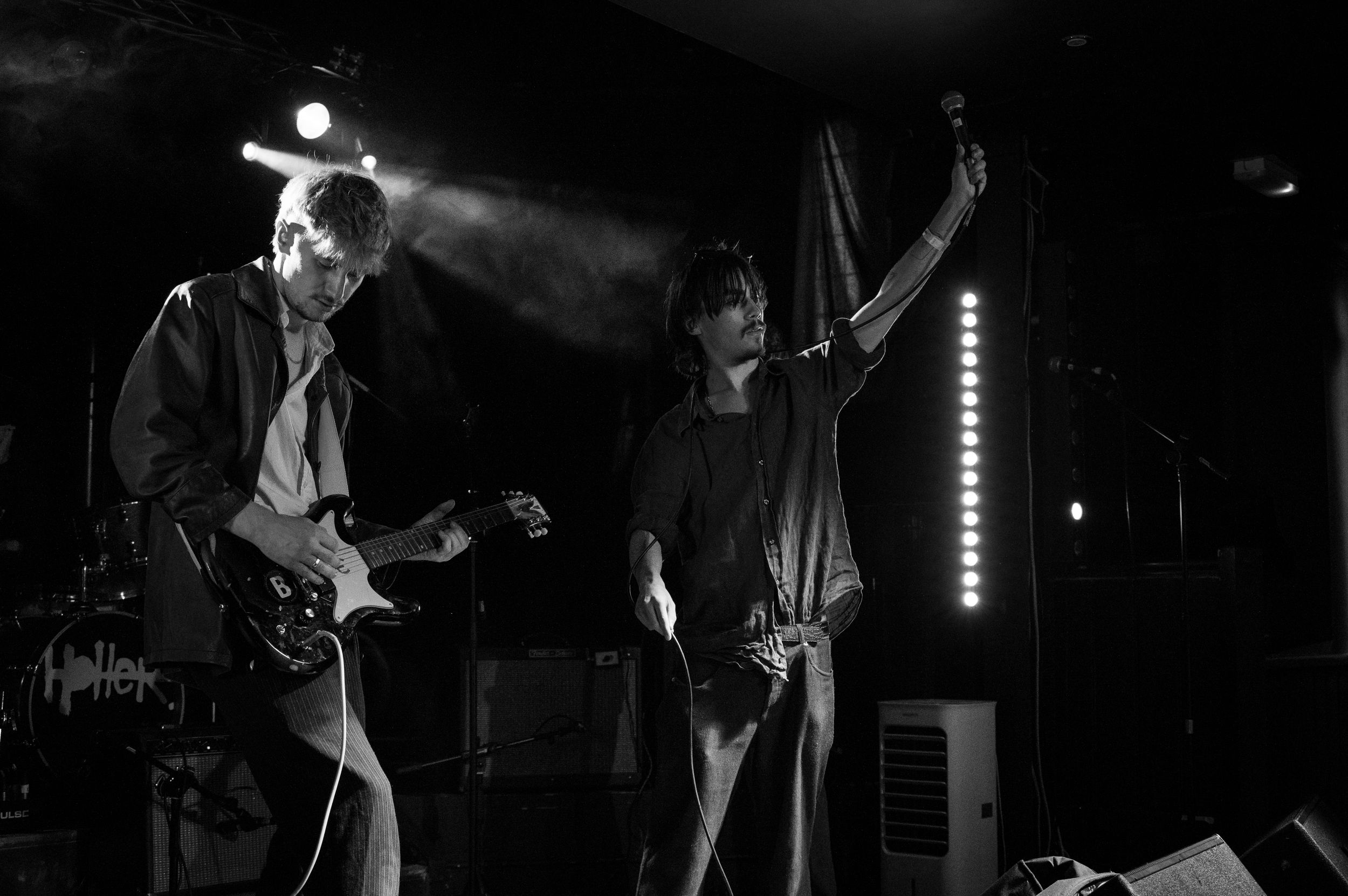 Two performers create dynamic energy on stage in black and white concert photography.