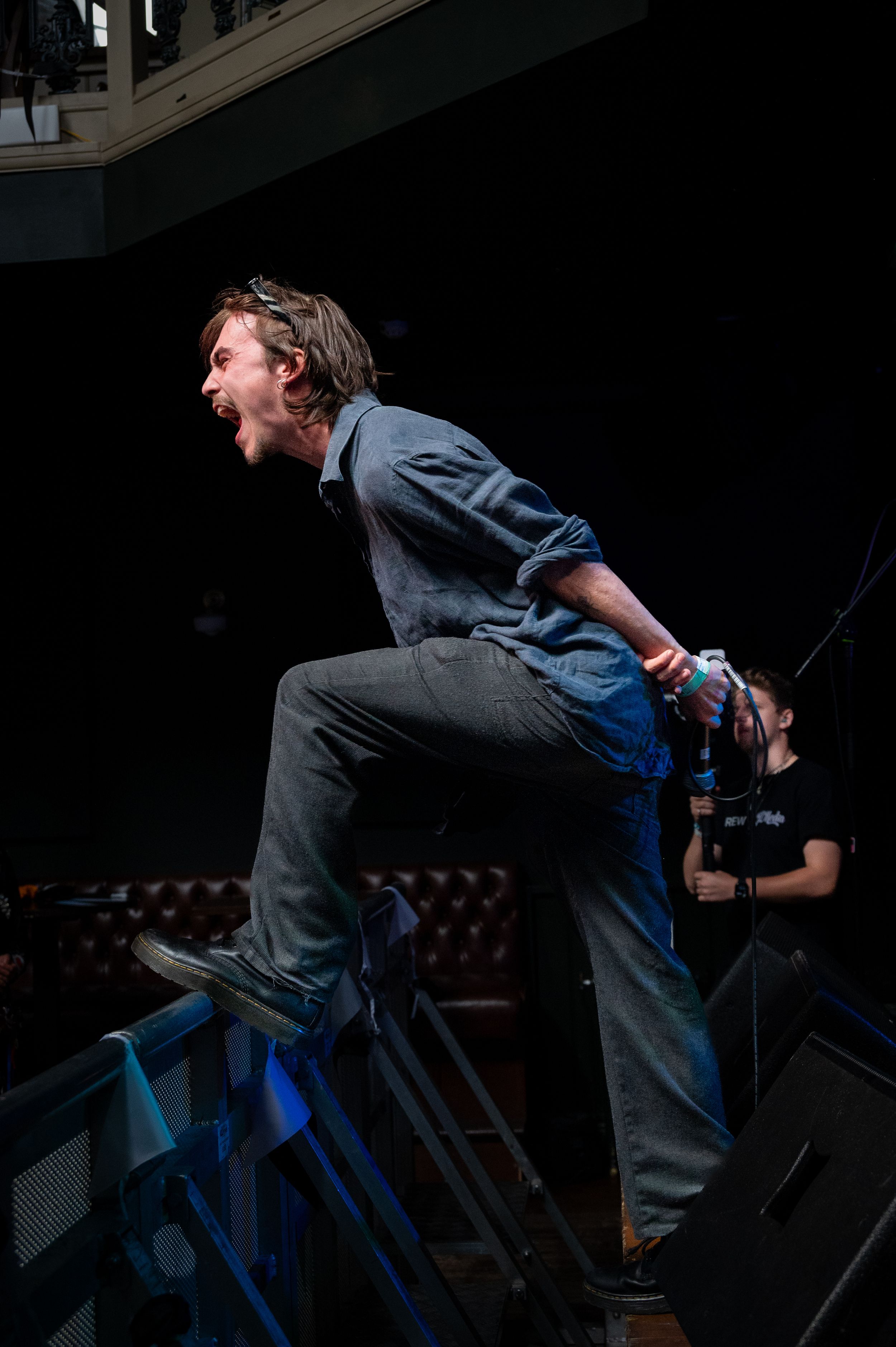 Performer leaps dramatically on stage during intense concert moment.