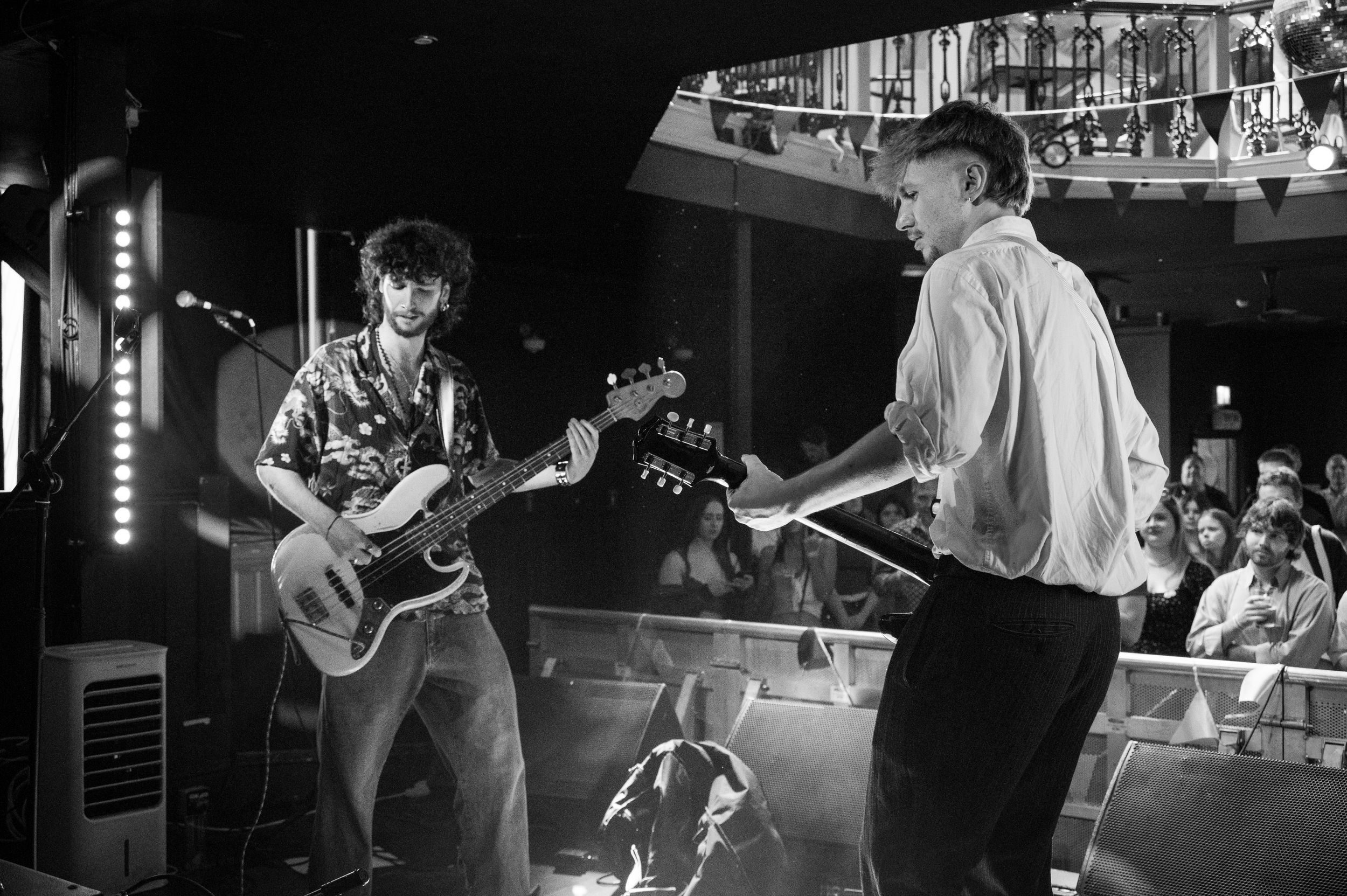 Black and white photo of two guitarists performing together on stage.