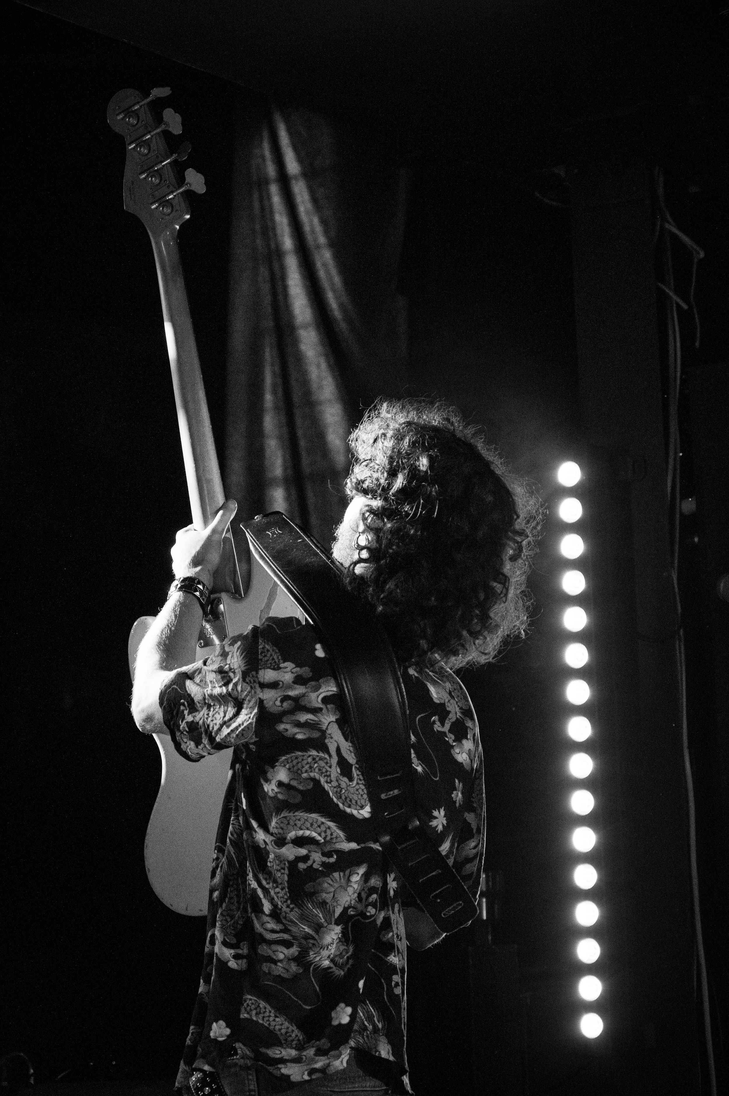 Black and white low angle shot of guitarist holding instrument up during performance.