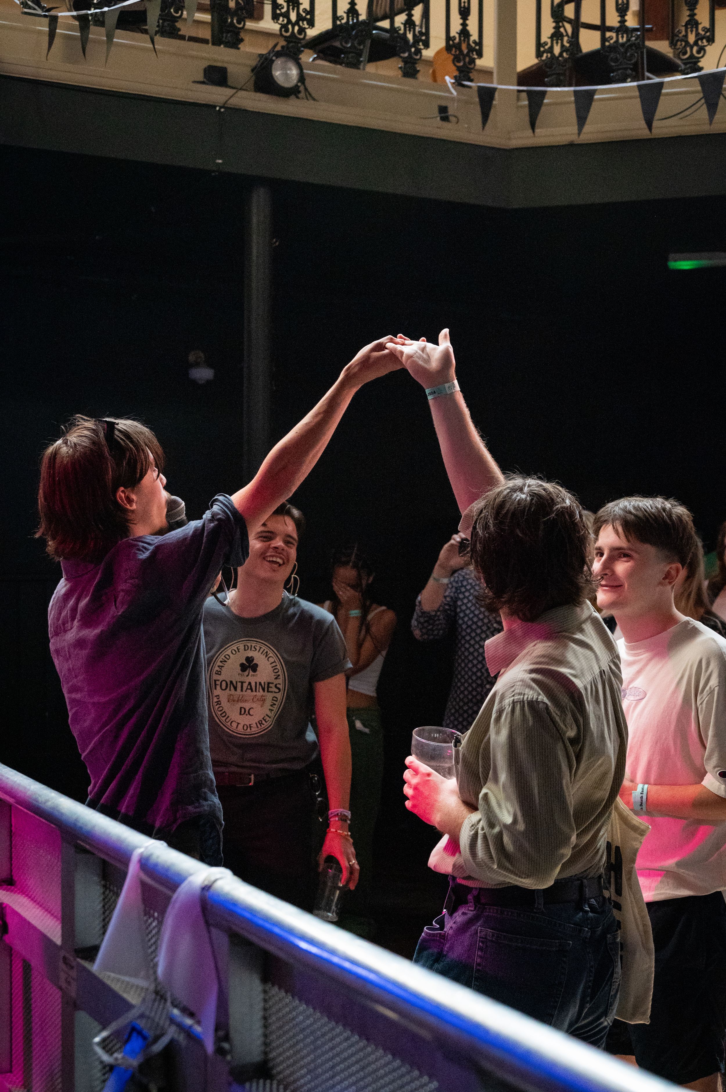Concert attendees high-five each other at a live music venue.