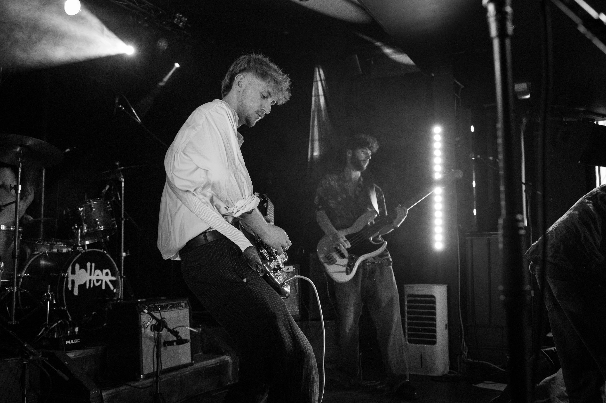 Musicians perform on stage in black and white during an intimate venue show.