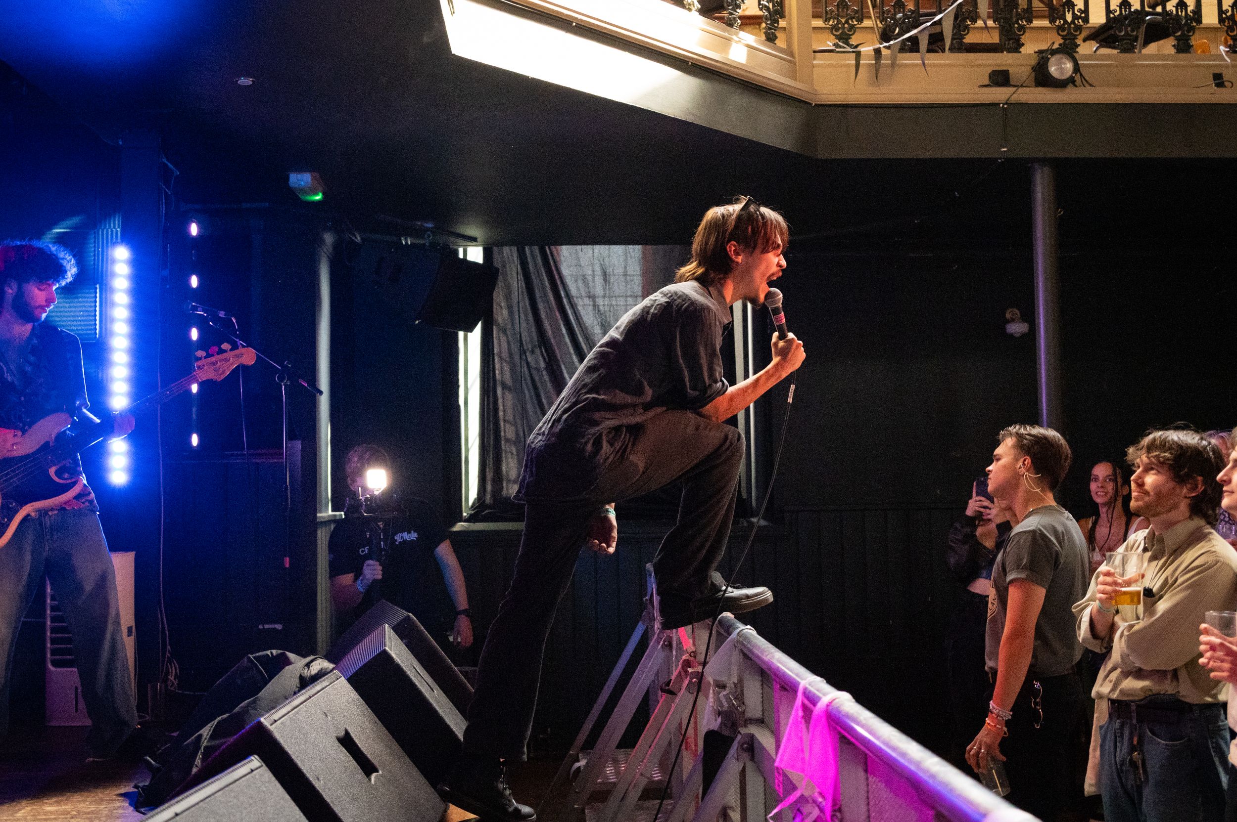 Performers engage with audience members during a live concert with blue lighting.