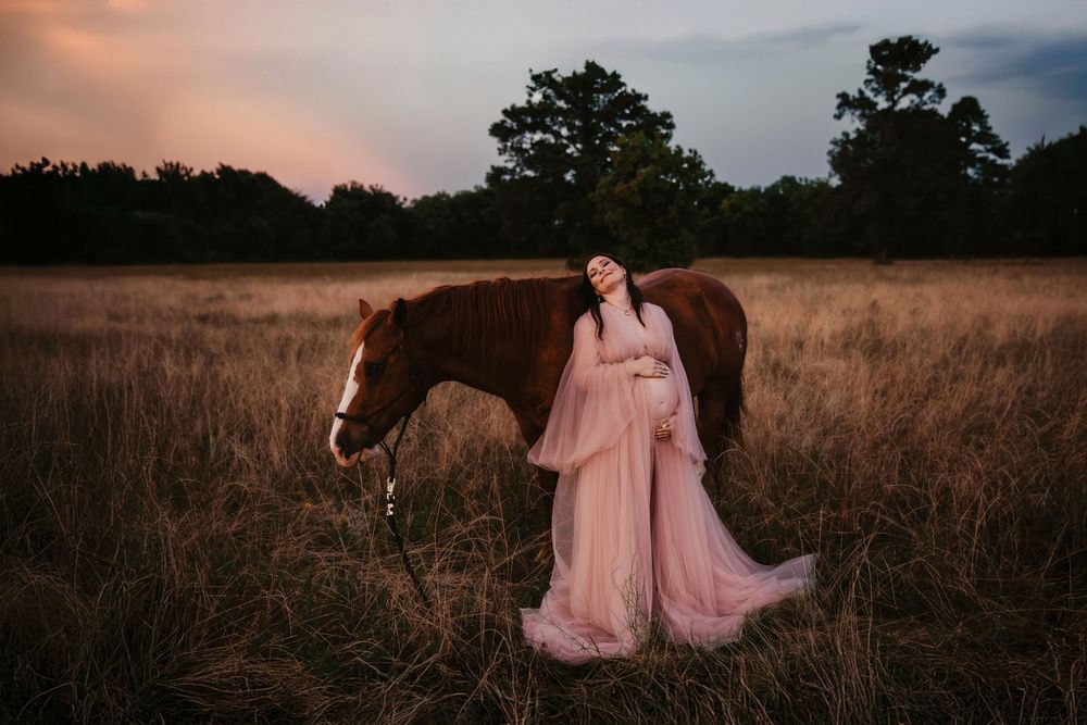 A woman in a flowing pink gown walks through a golden wheat field at sunset creating a dreamy atmosphere.