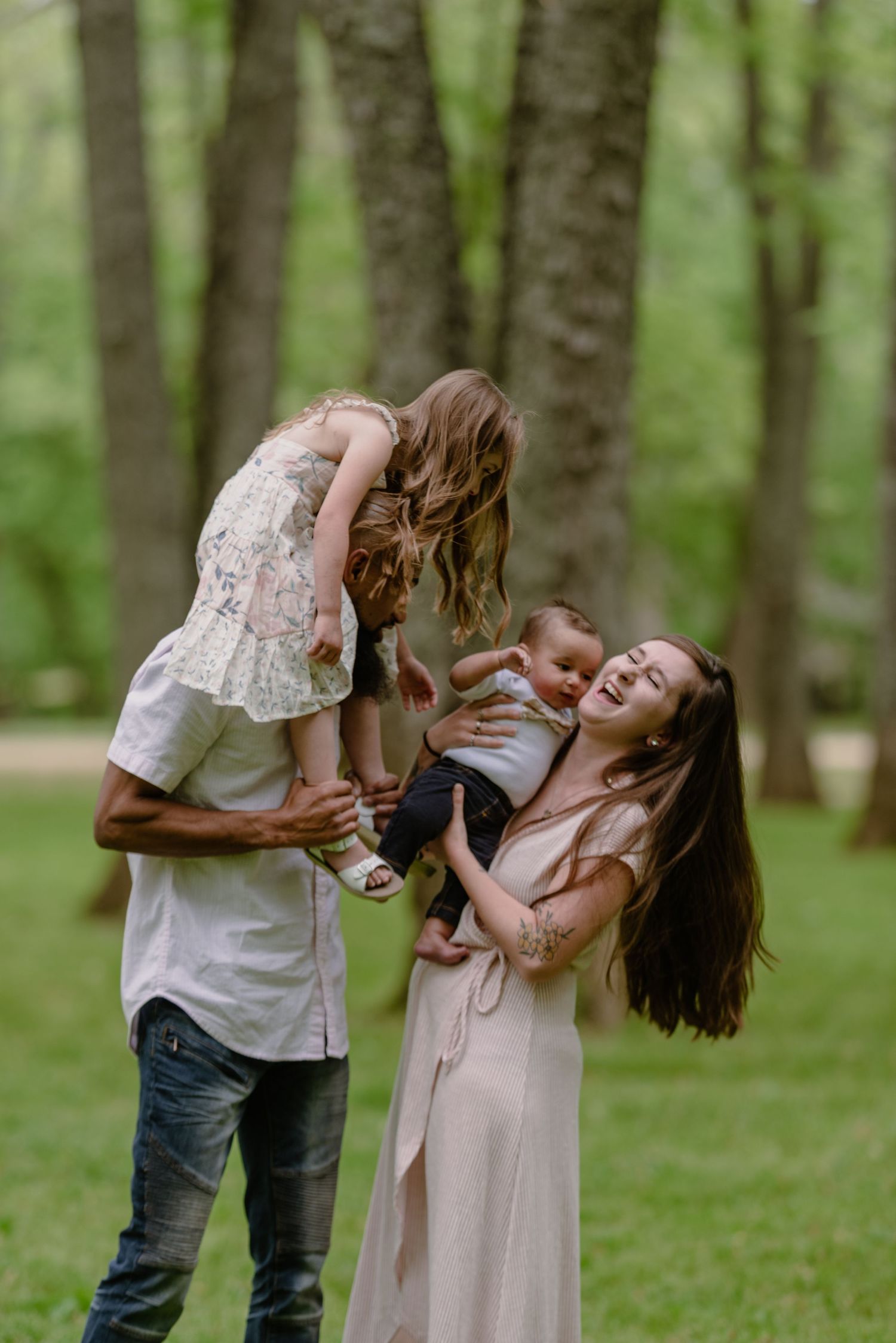 Family shares playful moment together in wooded setting during outdoor photoshoot.