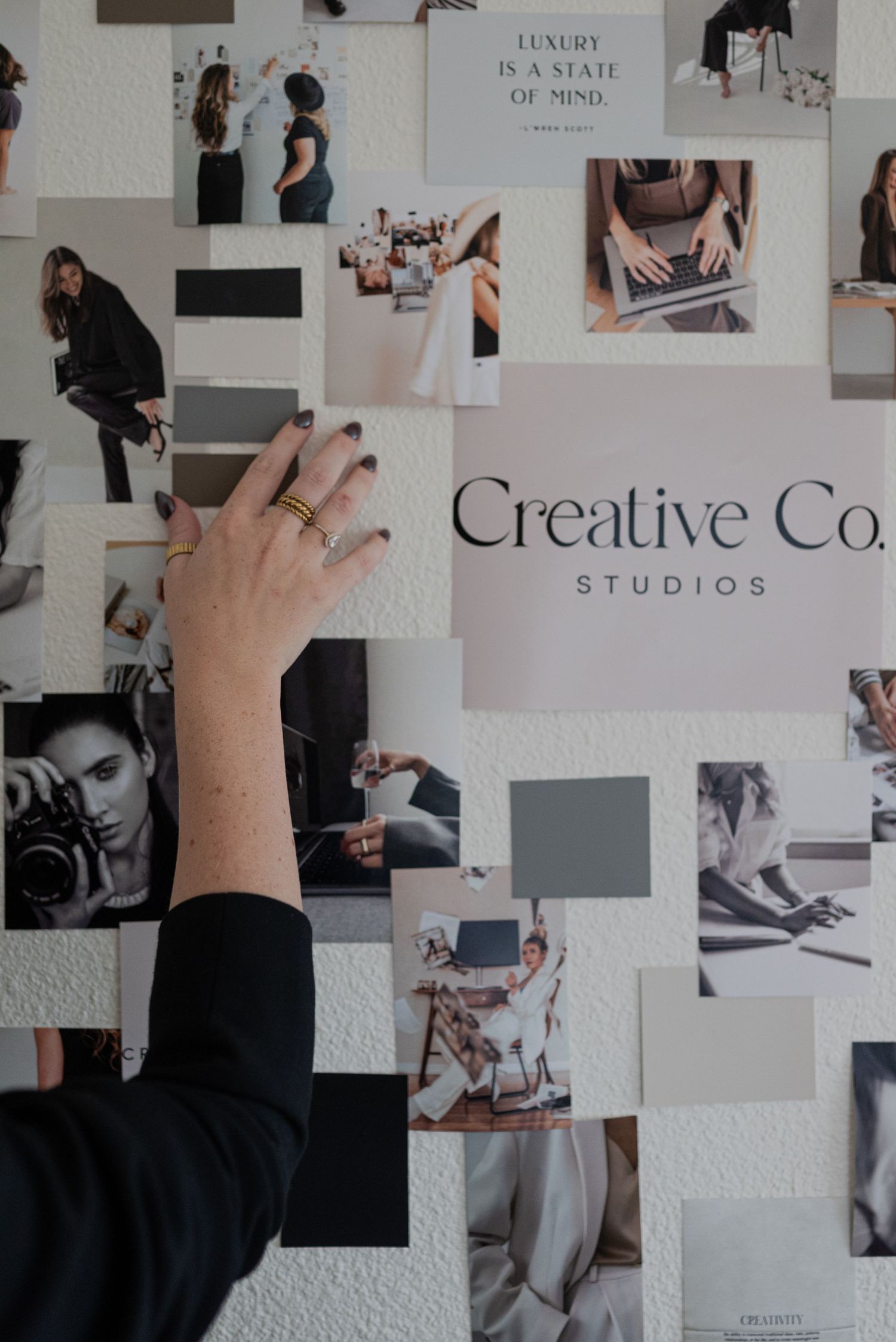 Hand reaching up to touch a creative mood board with black and white photography and text.