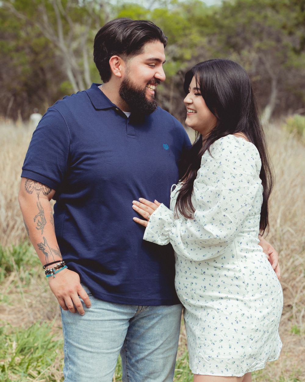 Couple in navy and mint green outfits posing together in field setting.