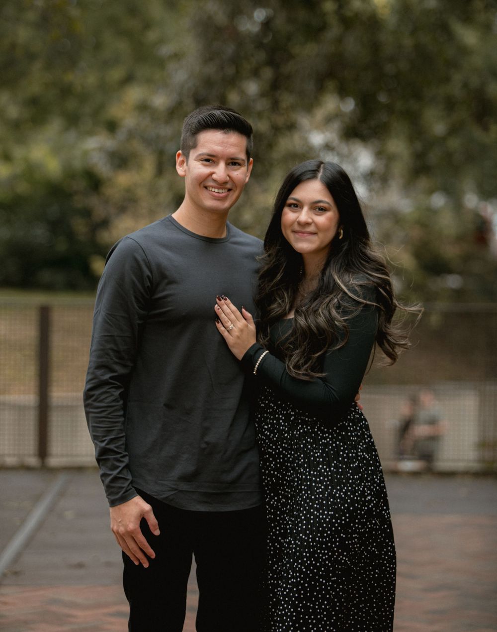 Romantic couple embracing outdoors wearing black and polka dot outfits.