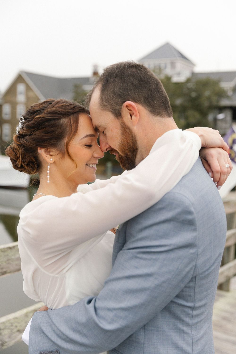 A tender embrace between newlyweds on a wooden boardwalk by the coast.