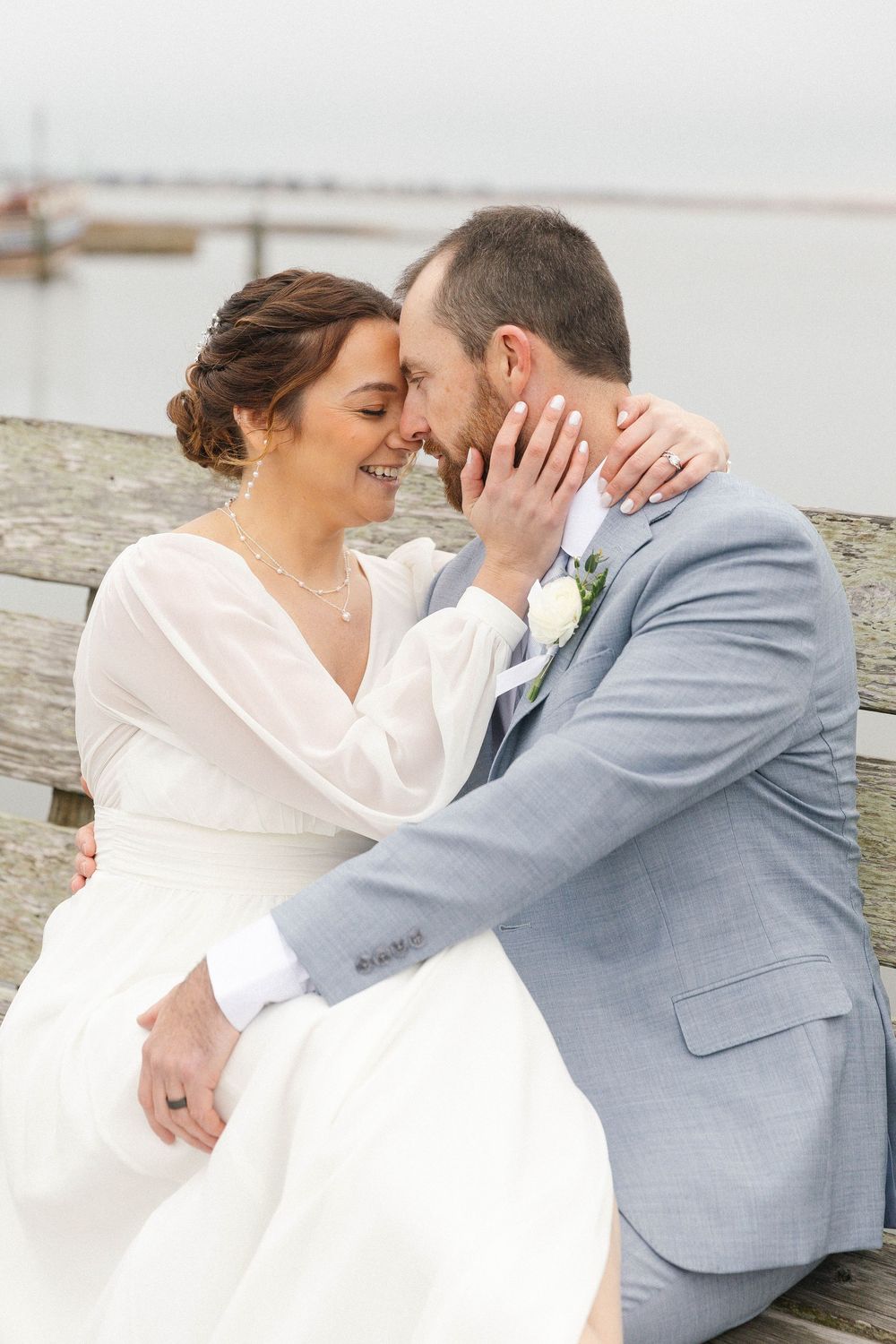 Romantic moment between a couple in formal attire on a waterfront deck.