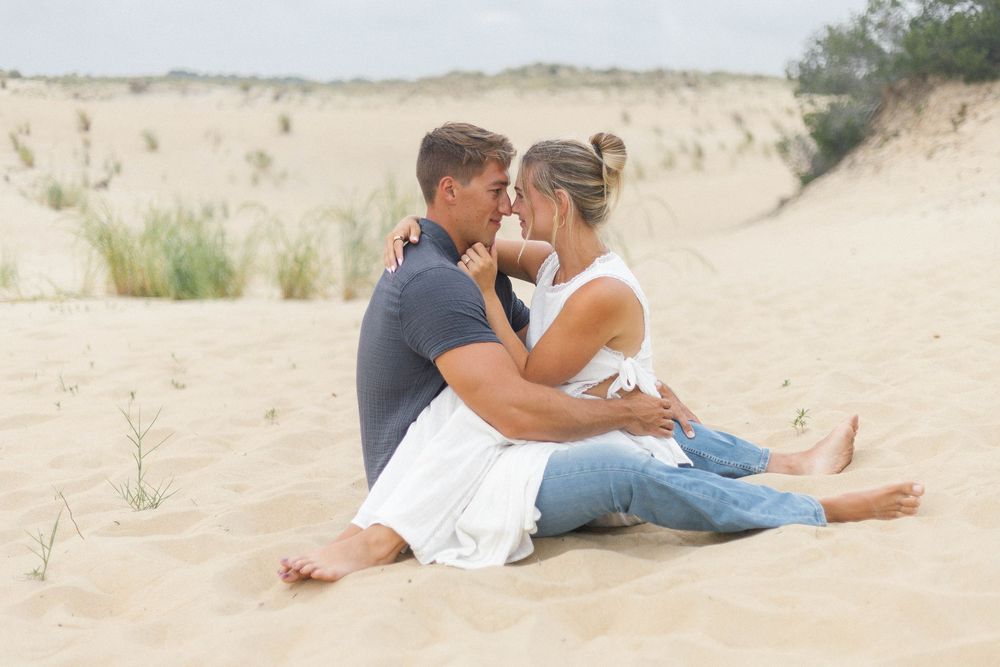 Couple sharing romantic moment while lounging on beach sand.