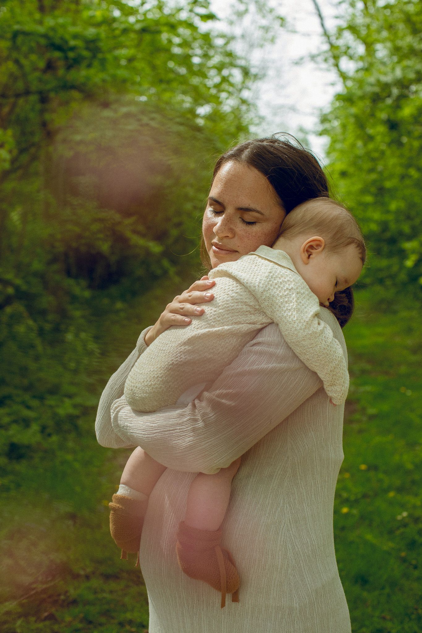 Tender moment captured in natural setting with white knit sweater and soft lighting.