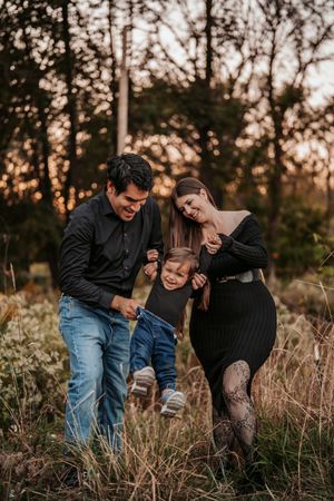 A family shares a joyful moment together while walking through a field at sunset with warm autumn lighting.