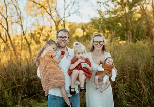 A joyful family shares laughter together during a golden hour photo session in a sunlit meadow.