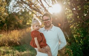 A parent and child share a tender moment in a sun-drenched field during golden hour.