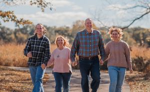 Family walking together on a dirt path during golden hour in autumn.