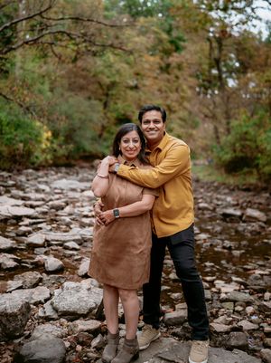 A joyful outdoor photoshoot on rocky terrain during autumn with warm earth-toned clothing and natural surroundings.