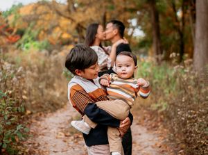 A loving family enjoys quality time together on an autumn path surrounded by golden foliage and natural scenery.