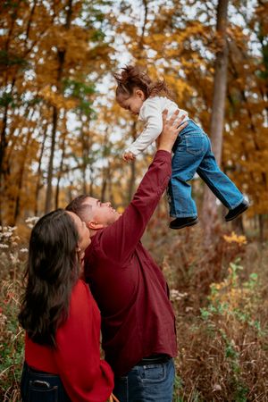 A couple shares joyful moments in a fall forest setting with golden autumn leaves in the background.
