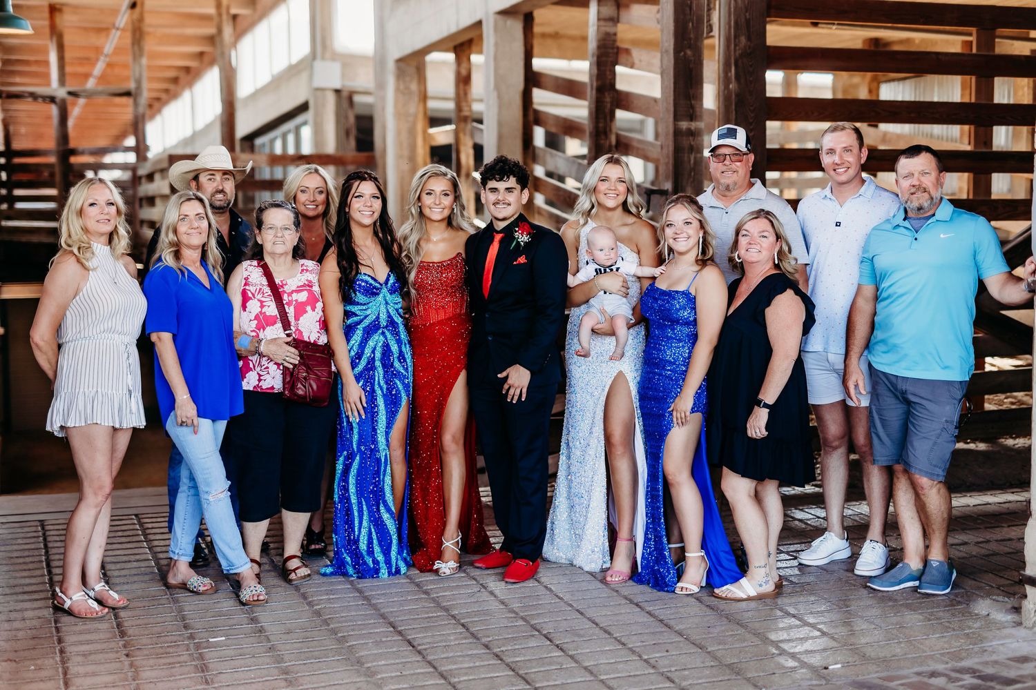 Large group poses together in formal attire against wooden wall background.