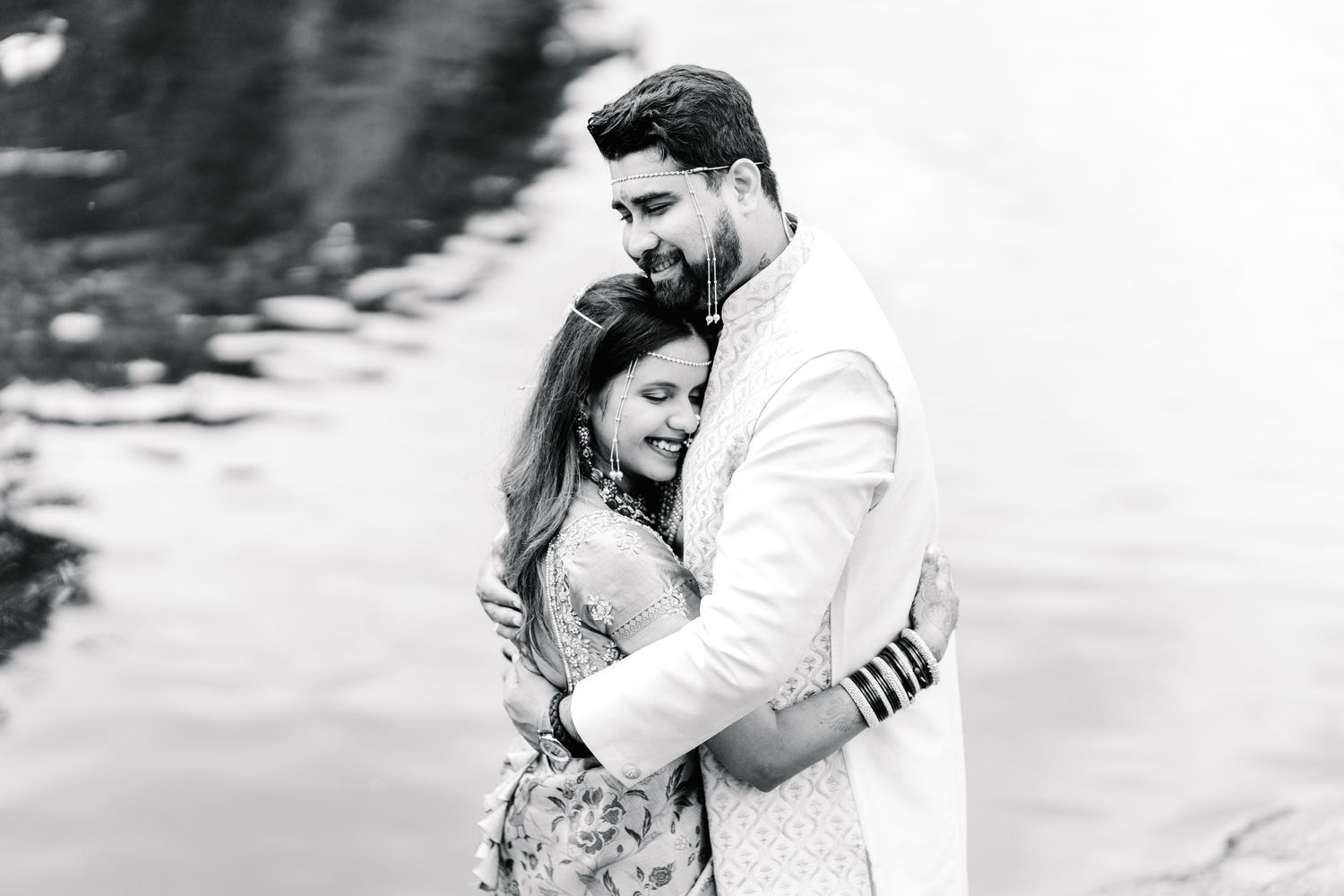 Black and white romantic portrait showing tender embrace against blurred background.