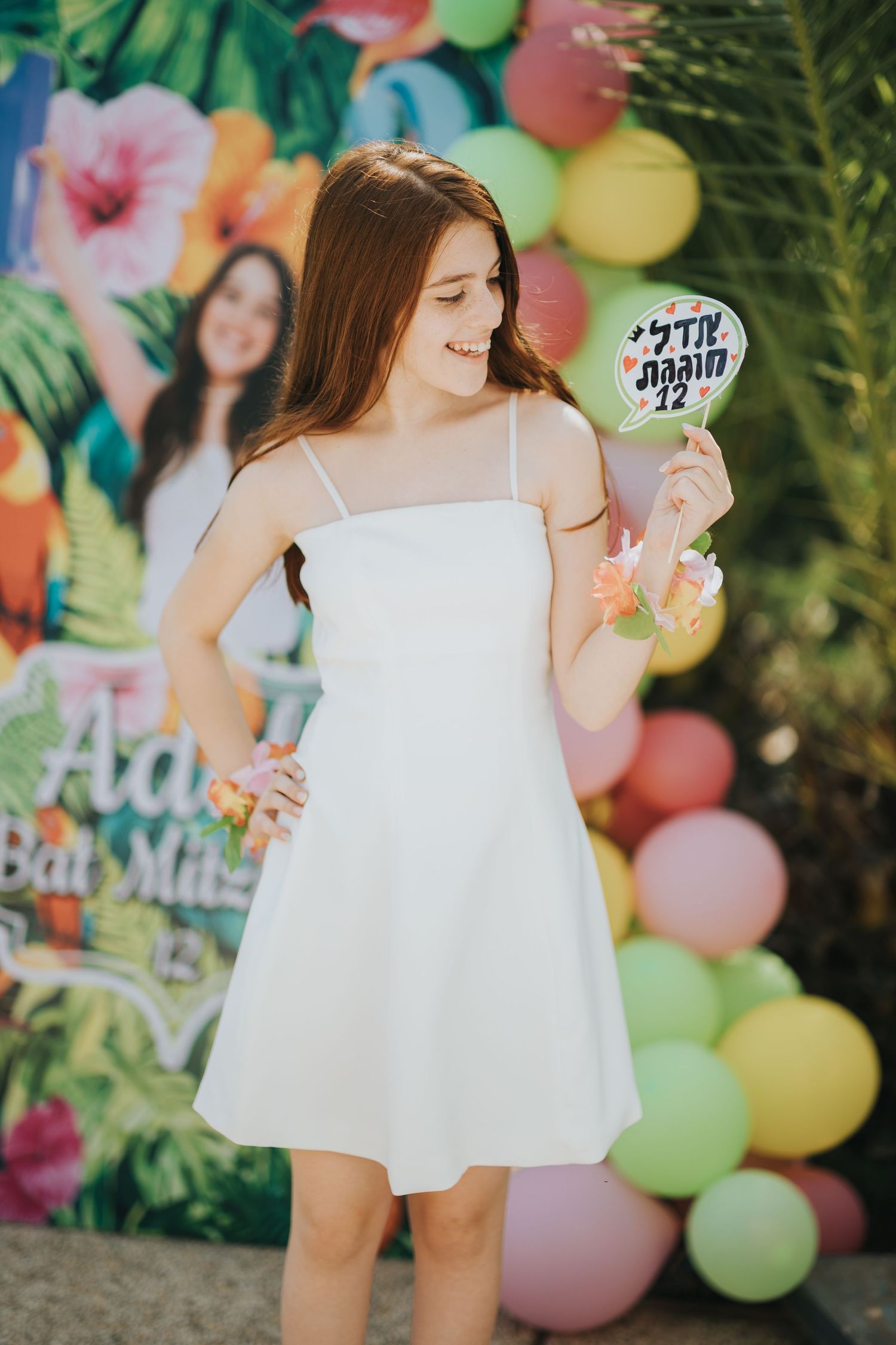 Celebration scene with white dress against colorful tropical balloon backdrop.