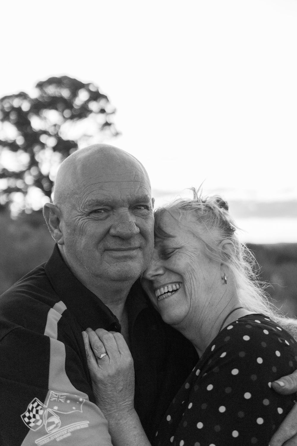 Couple embracing and laughing together during outdoor photo session.