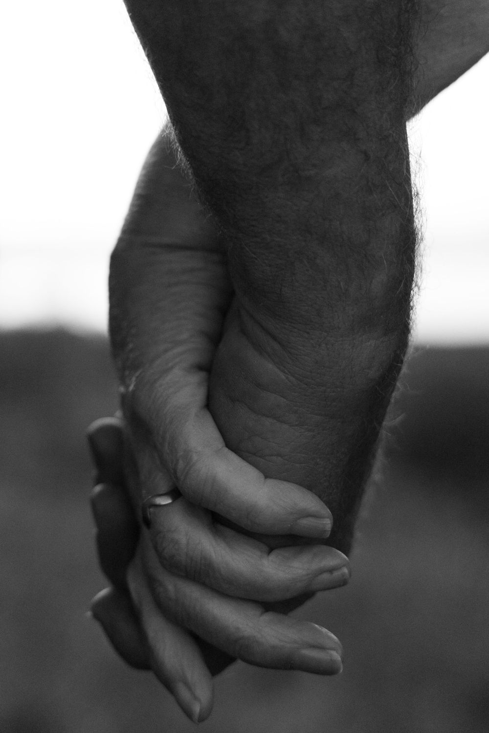 Close-up black and white image of two hands clasped together.