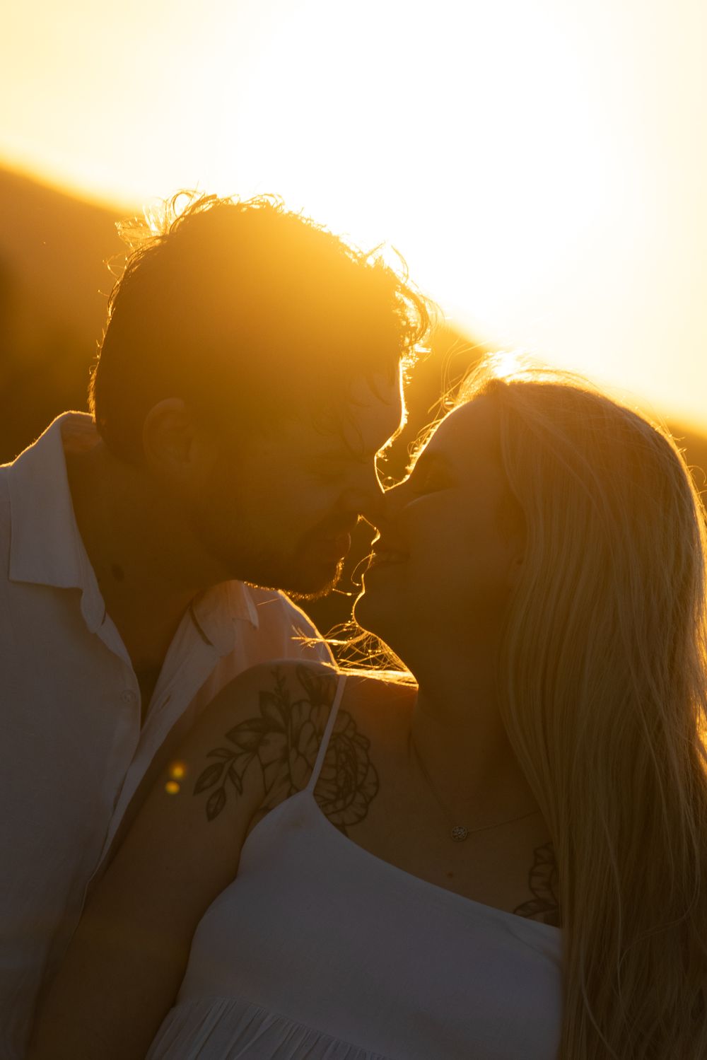 Silhouettes of two people against a bright golden sunset background.