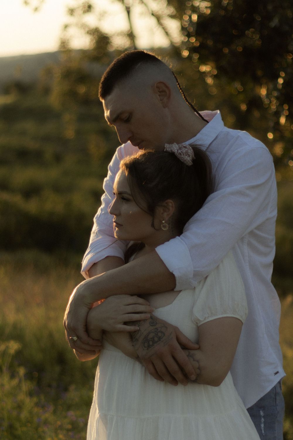 A romantic sunset maternity photoshoot features a couple embracing in golden light.