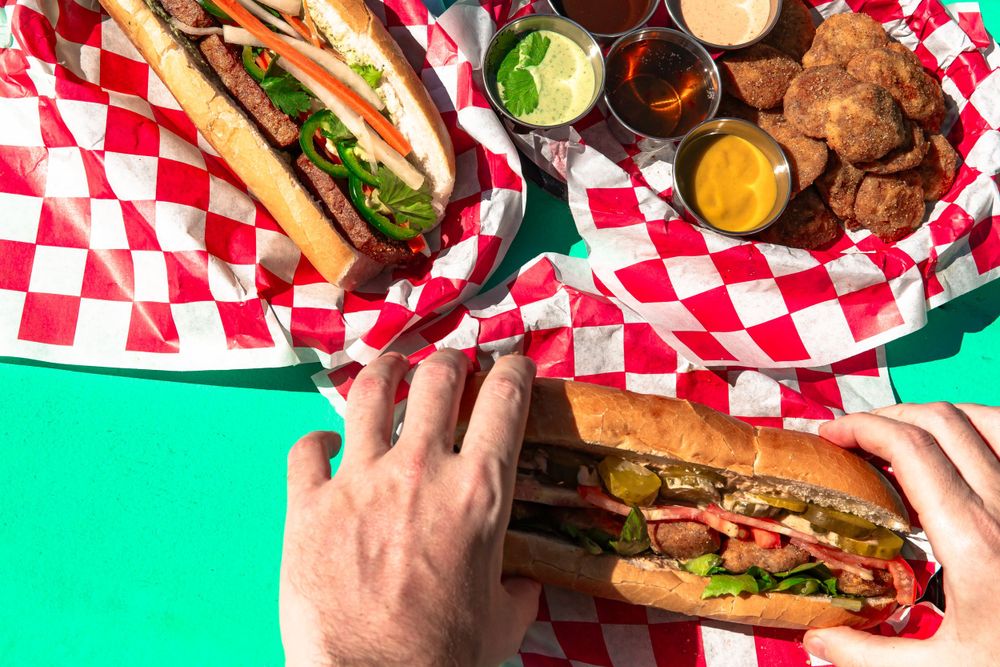 Hand grabbing sandwich from table