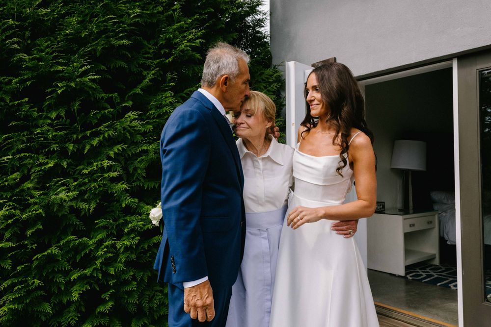 A heartwarming exchange between wedding guests on an outdoor deck near evergreen trees.