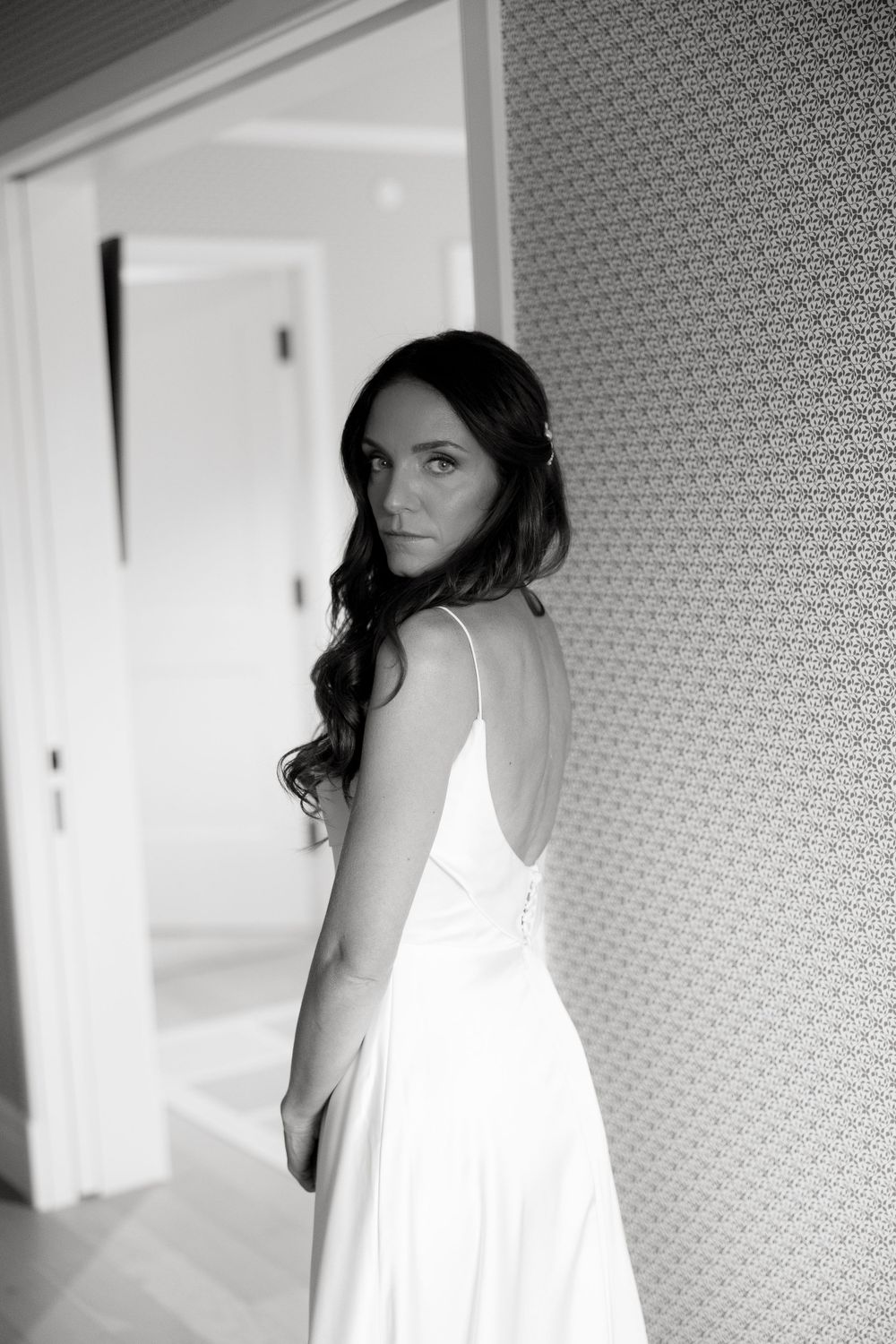 Black and white portrait of a bride in an elegant white dress looking over her shoulder.