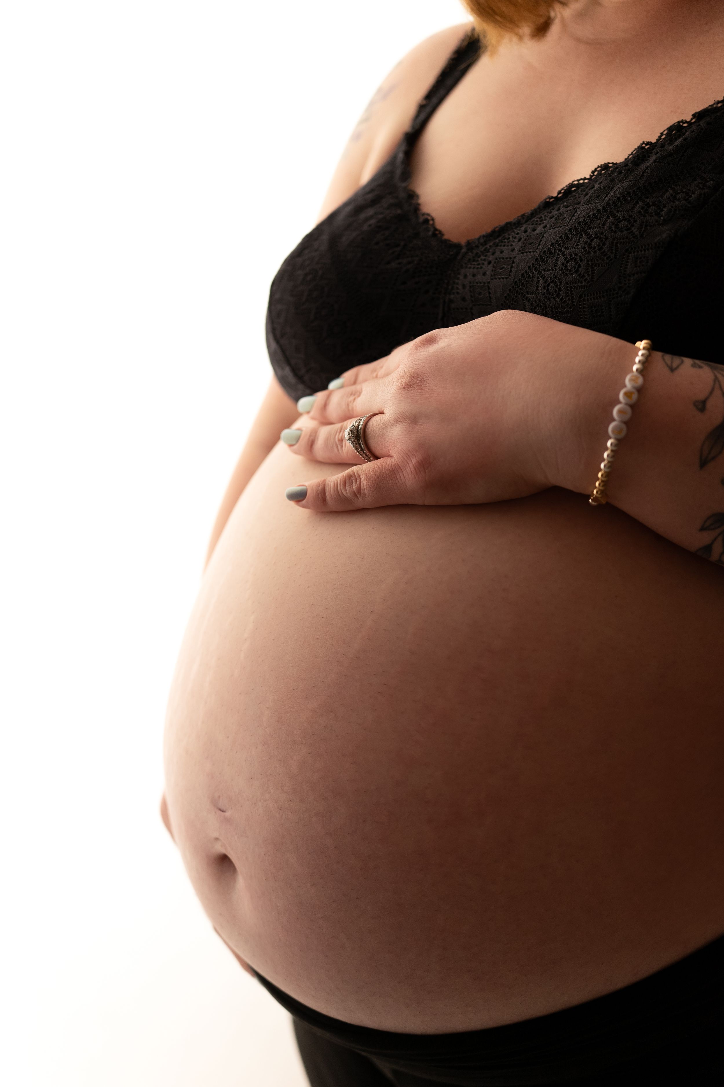 Close-up shots of a pregnant belly with hands wearing jewelry. Maternity photography session in Enumclaw, Washington by Maribelle Photograph