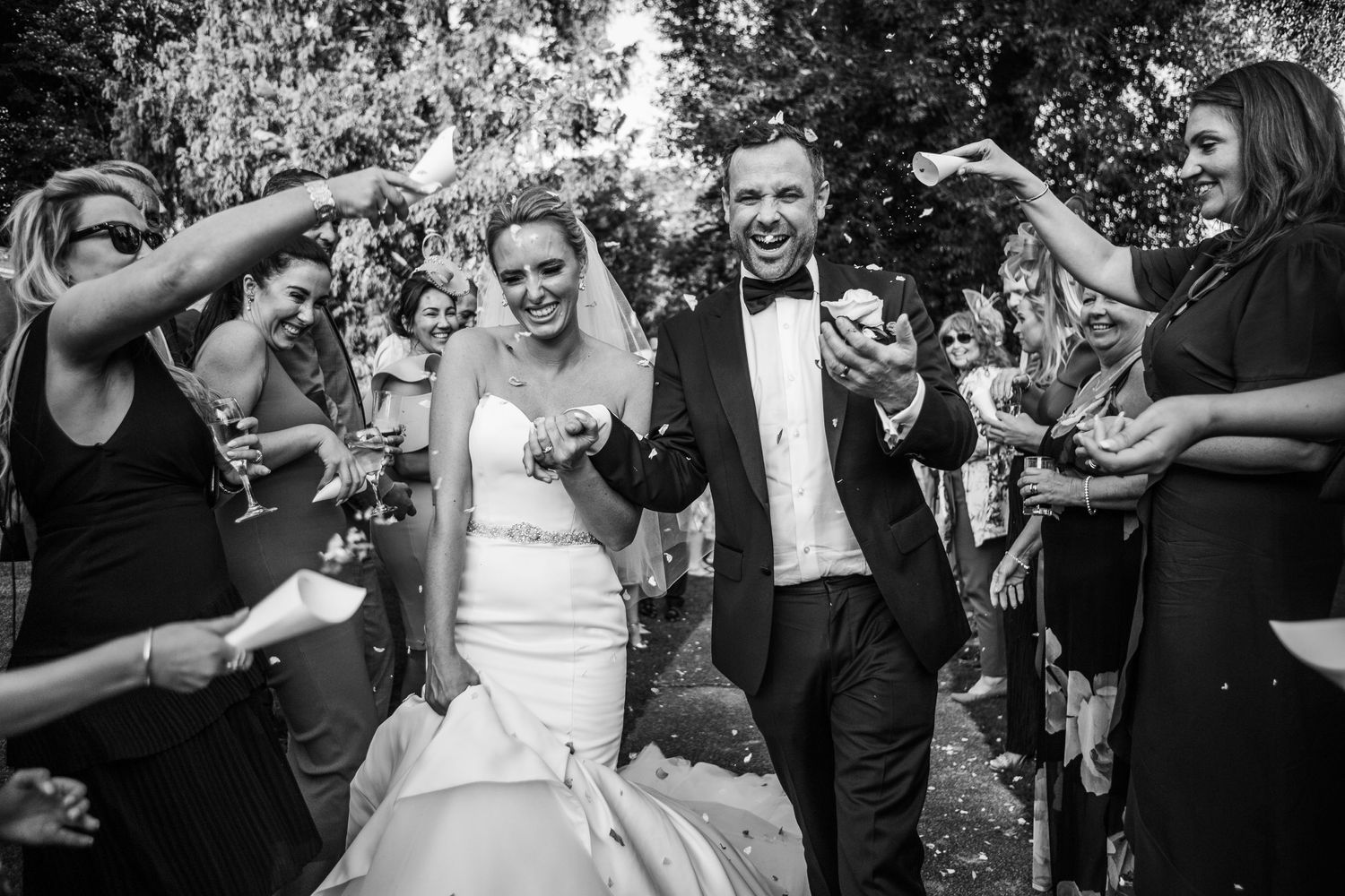 Joyful newlyweds walking through bubbles during wedding celebration recessional in black and white. The Orangery