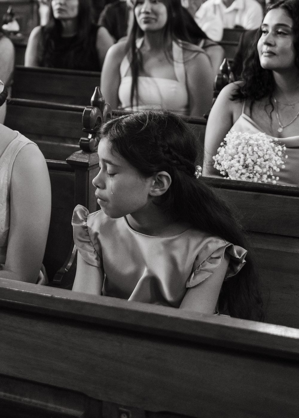 Black and white photo of people sitting in church pews during a service or ceremony.