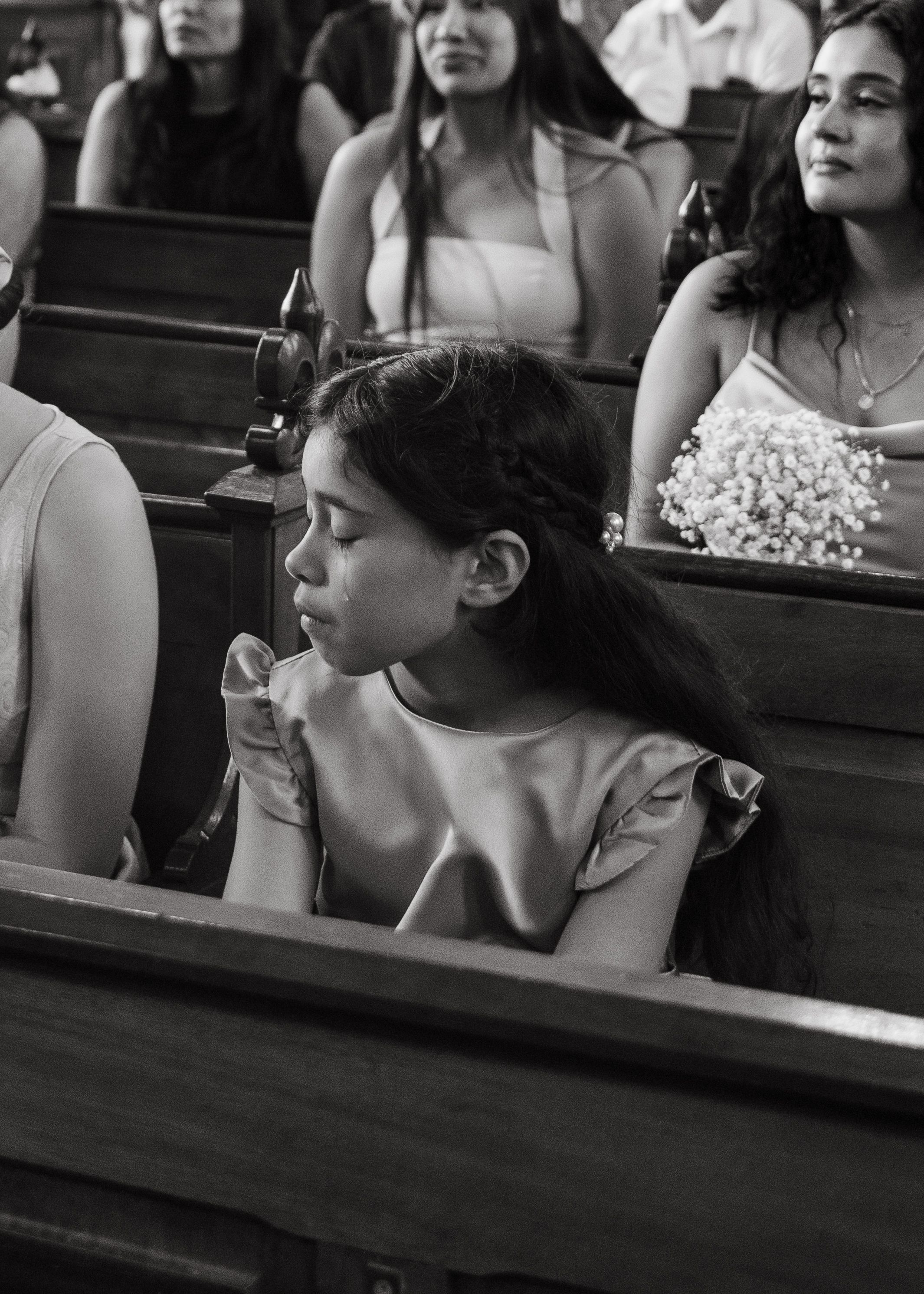 Black and white photo of people sitting in church pews during a service or ceremony.