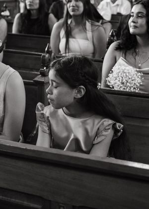 Black and white photo of people sitting in church pews during a service or ceremony.