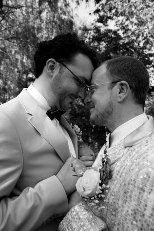 An intimate black and white wedding portrait of a couple sharing a tender moment outdoors.