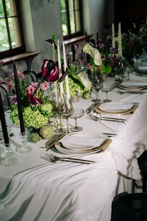 Elegant wedding reception table setting with white linens, black candles, and pink and green floral arrangements.