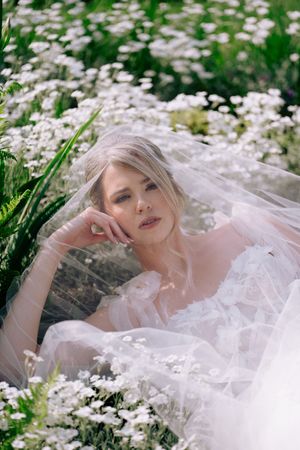 Ethereal bridal portrait in a field of white daisies with flowing veil and soft natural lighting.