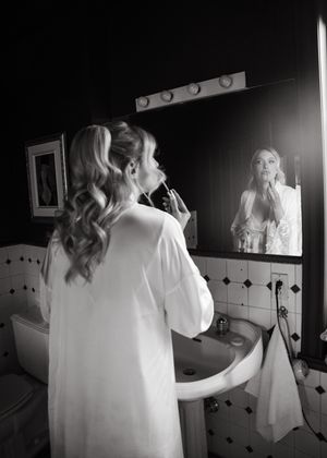Black and white photo series showing a bride getting ready in front of a bathroom mirror.