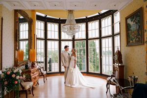 A panoramic view of an elegant ballroom interior with curved windows, chandeliers and ornate decor.
