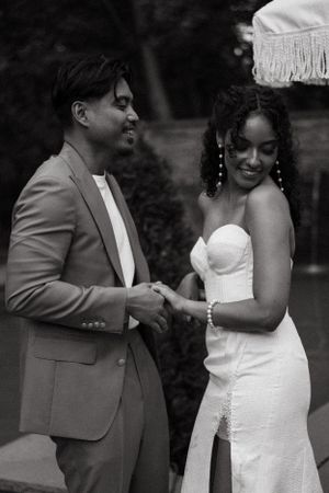 Black and white photo of couple sharing joyful moment at outdoor wedding.