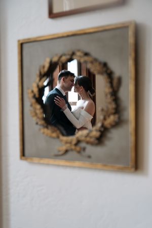 Romantic reflection of couple in ornate gold-framed mirror.