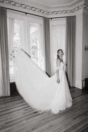 Black and white photo of bride in flowing dress with dramatic veil movement.