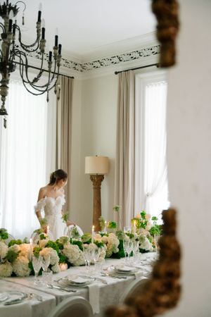 Elegant table setting with floral arrangements viewed through mirror reflection.