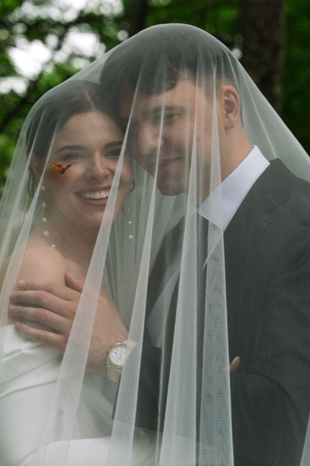 A romantic moment between newlyweds sharing an intimate moment under a sheer veil.