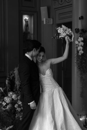 A joyful black and white wedding moment with the bride holding her bouquet high.