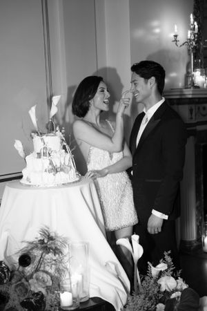 A candid moment of laughter between newlyweds next to their wedding cake.